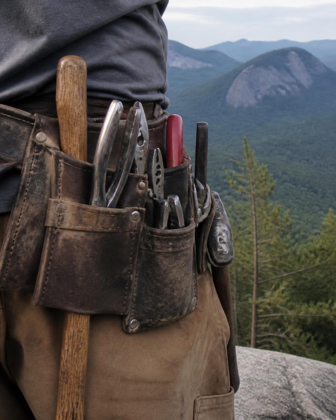 Tradesperson's tool belt with the North Carolina mountains behind